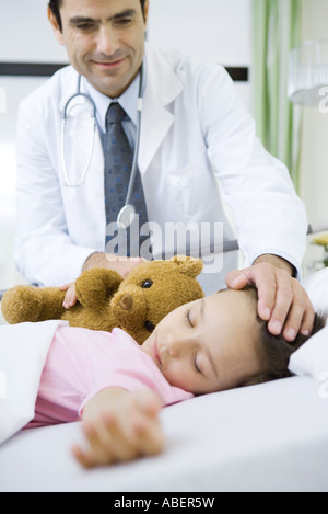 Arzt mit der Hand am Kopf des Kindes schlafen lächelnd Stockfoto