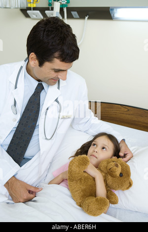 Arzt sitzt neben krankes Kind Stockfoto