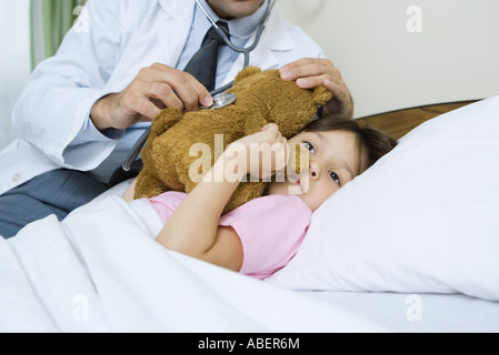 Arzt-Holding-Stethoskop, krankes Kind Teddybär Stockfoto