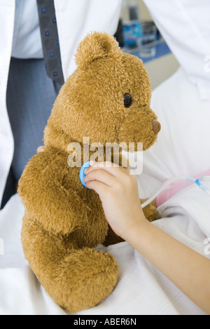 Kind hält Spielzeug Stethoskop, Teddybär, Teilansicht Stockfoto