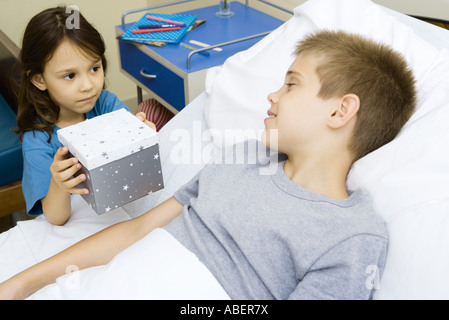 Junge im Krankenhausbett empfangen von Mädchen Stockfoto