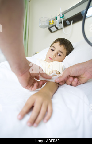 Junge im Krankenhausbett liegend, mit IV mit Klebeband um wappnen Stockfoto
