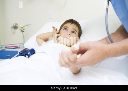 Junge im Krankenhausbett liegend, blickte zu Arzt Stockfoto