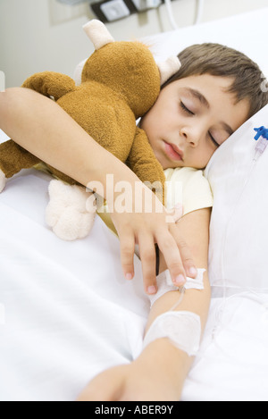 Junge liegend im Krankenbett, Holding gefüllte Tier Stockfoto