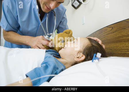 Mädchen im Krankenhausbett liegend, lächelte Krankenpfleger Stockfoto
