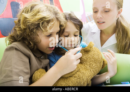 Jungen und Mädchen spielen Arzt mit Teddybär Stockfoto