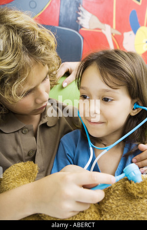 Jungen und Mädchen spielen Arzt mit Teddybär Stockfoto