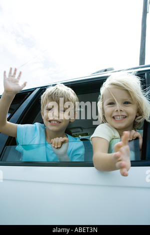 Kinder stecken Köpfe aus Autofenster, winken Stockfoto