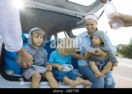 Kinder essen hinter dem Auto Stockfoto