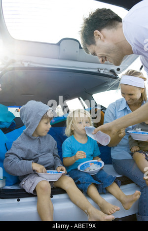 Kinder essen hinter dem Auto Stockfoto