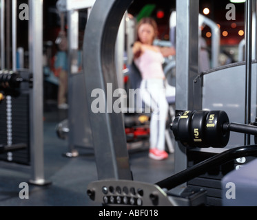 Junge Frau, die Arbeiten am Gerät für Krafttraining im Fitnessstudio Stockfoto