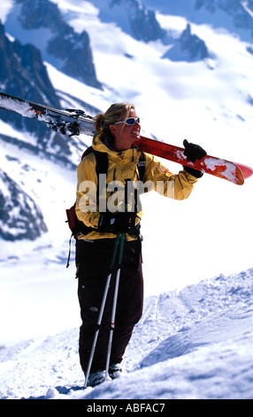 Skifahrerin mit ihren Skiern auf die Schulter bergauf wandern Stockfoto
