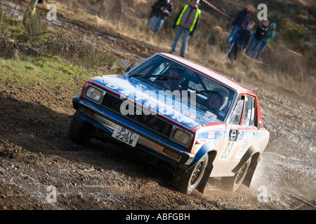 Schlammigen roten weißen und blauen Nissan Datsun Violet Rallyeauto fahren auf Schotter Steinen und Schlamm Stockfoto