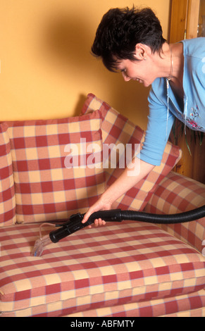 mittlere gealterte Frau Staubsaugen Tuch bedeckt sofa Stockfoto