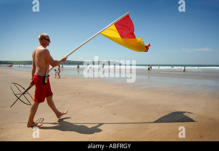 Ein Rettungsschwimmer bewegen die rot-gelben Flagge am Strand von Woolacombe Bay, North devon Stockfoto