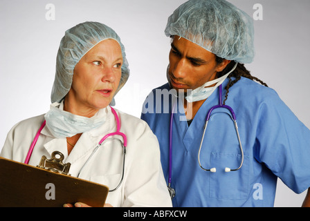 Weiblichen Oberarzt mit Diagramm auf Clip Board und Stethoskop Rücksprache mit jungen schwarzen Doktor im Haarnetz Stockfoto