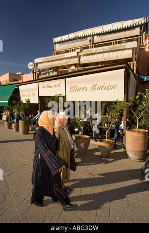 Zwei Frauen in traditioneller Kleidung gehen vorbei an modischen Restaurant Platz Djemaa El Fna Marrakesch Marokko Stockfoto