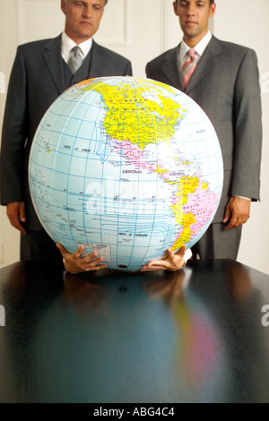zwei Geschäftsleute Blick auf aufblasbaren Globus gehalten von zwei Händen Americas prominente Stockfoto