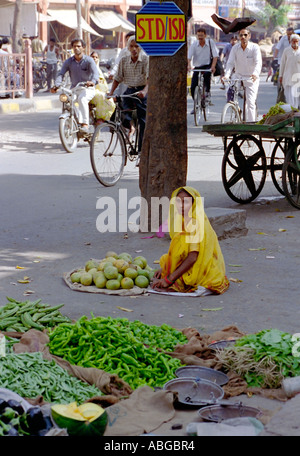 Frau sitzt auf Dorfplatz Verkauf von Gemüse in Indien mit Schild mit der Aufschrift STD ISD über Ihr Stockfoto