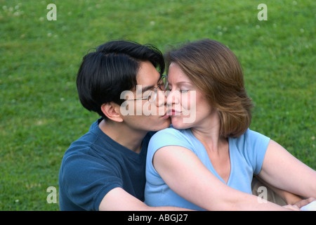 Interracial paar sitzt auf einer Wiese in einem park Stockfoto