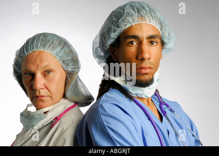 Nahaufnahme von schweren männlichen und Ärztin Arzt Team junge schwarze stellen und ältere weiße Frau in Scrubs mit Haarnetz und OP-Maske entfernt Stockfoto