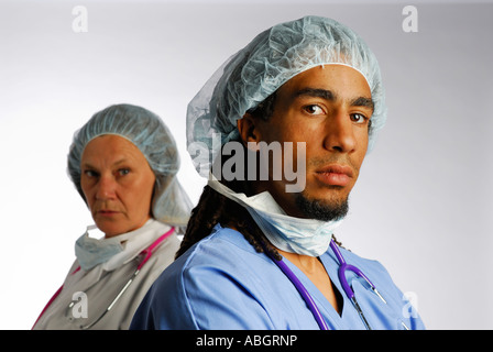 Ernste junge schwarze junior Arzt auf Ärzteteam mit älteren Ärztin in Scrubs Haarnetz und Mundschutz gesenkt Stockfoto