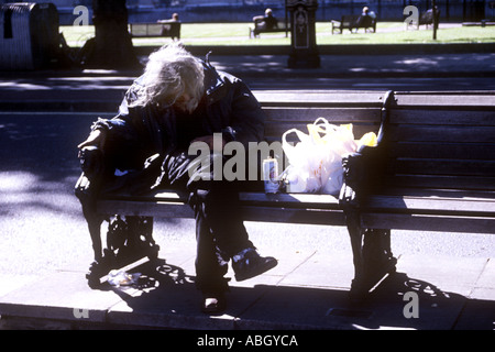 Obdachloser mit Dose Bier und seine wenigen Habseligkeiten auf Böschung London UK Stockfoto