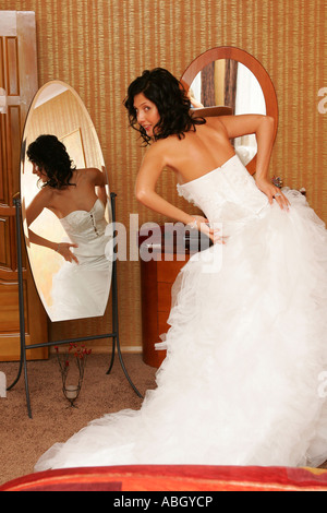 Eine Braut am Tag ihrer Hochzeit ihr Dess im Spiegel zu betrachten. Sie ist ein traditionelles weißes Brautkleid tragen. Stockfoto