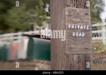 Einen selektiven Fokus Farbbild eines rustikalen Zeichens für eine Privatstraße mit Briefkästen und Pferde im Hintergrund sichtbar Stockfoto