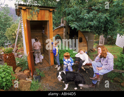 Kinder und Mutter warten auf Familie dunny zu benutzen oder Nebengebäude im Land nach Hause Hinterhof in Tasmanien Australien Stockfoto