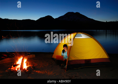 Frau mit Laptop in Notzelt auf die Ufer der Funken See von einem knisternden Feuer im Deschutes National Forest Oregon Camping Stockfoto