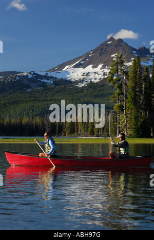 Paar Paddeln im roten Kanu auf Sparks Lake unter gebrochen oben Berg im Frühjahr Deschute National Forest Oregon Stockfoto