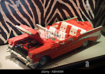 Detailliertes rotes 87 Chevrolet Bel Air-Modell aus Lego-Sets mit offener Kapuze und weißer Innenseite vor einem Hintergrund mit Zebramuster. Stockfoto
