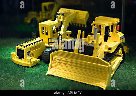 Detaillierte gelbe Caterpillar-Planierraupe aus Lego-Sets auf grünem Gras. Stockfoto