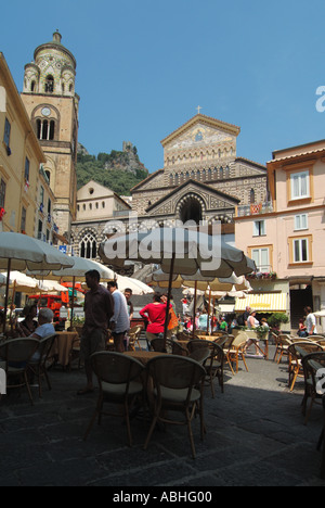 Amalfi historische, römisch-katholische Kathedrale, die von einer Bar im Freien, einem Café mit Sonnenschirmen versteckt ist, auf der geschäftigen Piazza del Duomo mit dem Glockenturm Salerno Campania Italien Stockfoto