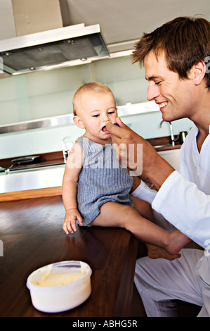 Vater und Sohn in der Küche, Mann Fütterung sein Baby im Haus Stockfoto