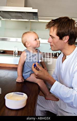 Vater und Sohn in der Küche, Mann Fütterung sein Baby im Haus Stockfoto