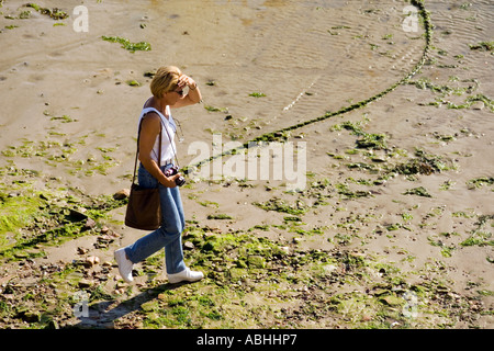 HERR FRAU MIT EINER KAMERA, DIE ZU FUß IN ERQUY HAFEN BEI EBBE BRETAGNE FRANKREICH Stockfoto