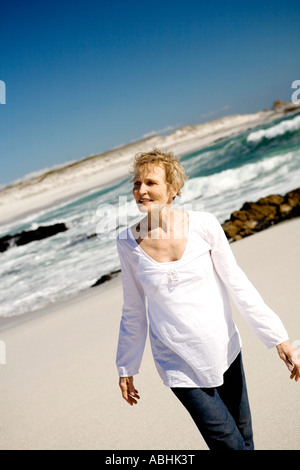 Ältere Frau, die zu Fuß am Strand Stockfoto