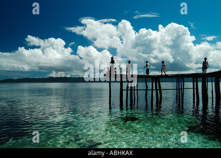 Papua Kinder Angeln vom Steg auf einer kleinen Insel in Raja Ampat Stockfoto