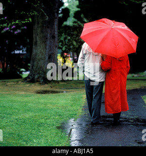 PAAR IM REGEN SPAZIEREN Stockfoto