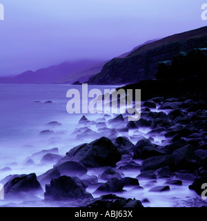 Ein felsiger Strand auf der Insel Skye erschossen in der Abenddämmerung mit einer langen Belichtungszeit die Wellen rund um die Felsen wird misty blue Stockfoto