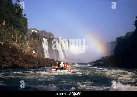 Iguaçu-Wasserfälle, Bundesstaat Parana, Brasilien. Touristen auf dem Boot am Fuße der Wasserfälle; Regenbogen. Stockfoto