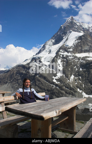 Schweiz Wallis das Matterhorn A Mädchen in ihrer Mitte der 20er Jahre genießt einen Drink und schöner Aussicht auf die Alpen von außen Schonbielhutte Stockfoto