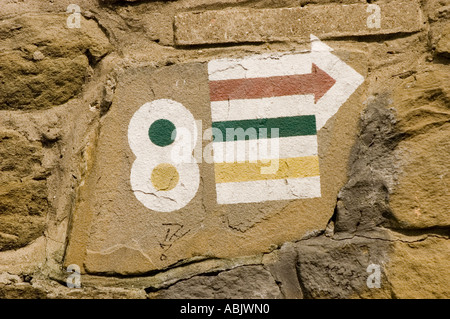 Gemalte Pfeile und die Nummer 8 auf einer Steinmauer, die einen Wanderweg in Polen markiert. Stockfoto