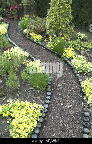 Flasche scharfkantigen Pfad in einem Frühlingsgarten mit Polyanthus und Primeln kann Norfolk Stockfoto