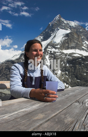 Schweiz Wallis das Matterhorn A Mädchen in ihrer Mitte der 20er Jahre genießt einen Drink und schöner Aussicht auf die Alpen von außen Schonbielhutte Stockfoto