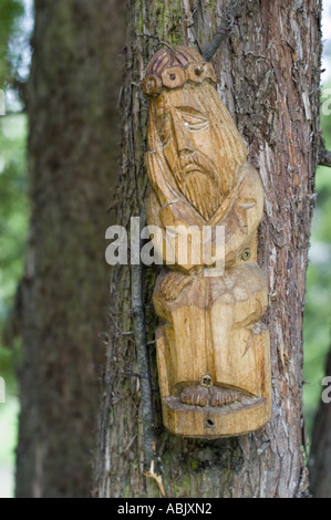 Polnische alte traditionelle Holzskulptur des römisch-katholischen heiligen an einem Baumstamm befestigt, volkstümliche Schnitzerei in Polen. Stockfoto