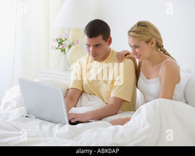 Paar auf der Suche am Laptop im Bett Stockfoto