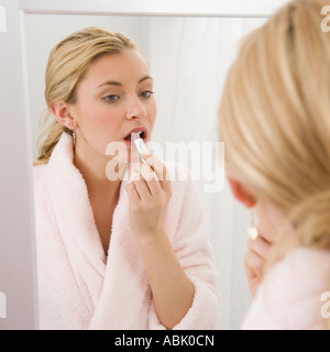 Frau Auftragen von Lippenstift im Spiegel Stockfoto